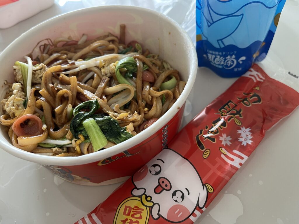 デリバリー容器に入った焼きそば、割りばし、ジュース